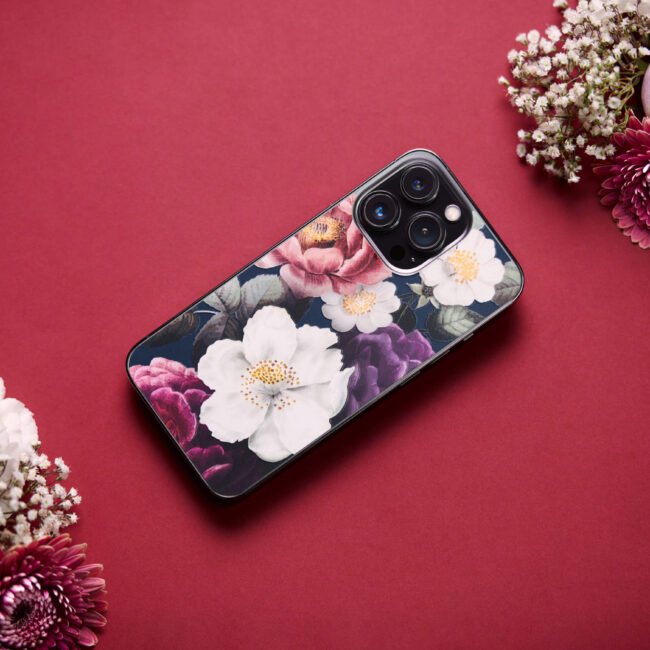 Product photo of a phone skin from Rabbiter with flowers on it. Surrounded with flowers on a red background for a beautiful and minimalistic look.