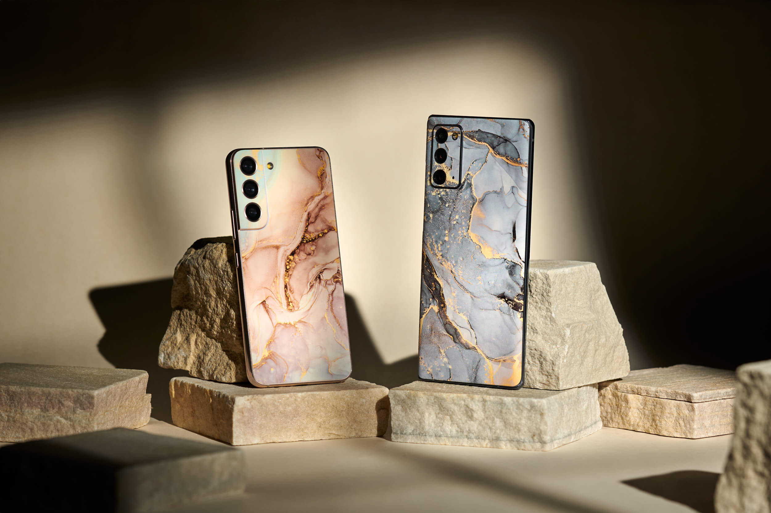 Product photo of two phone skins from Rabbiter with marble optic. Placed on stones for the strong and grounded feeling with shades of color as in the skins.