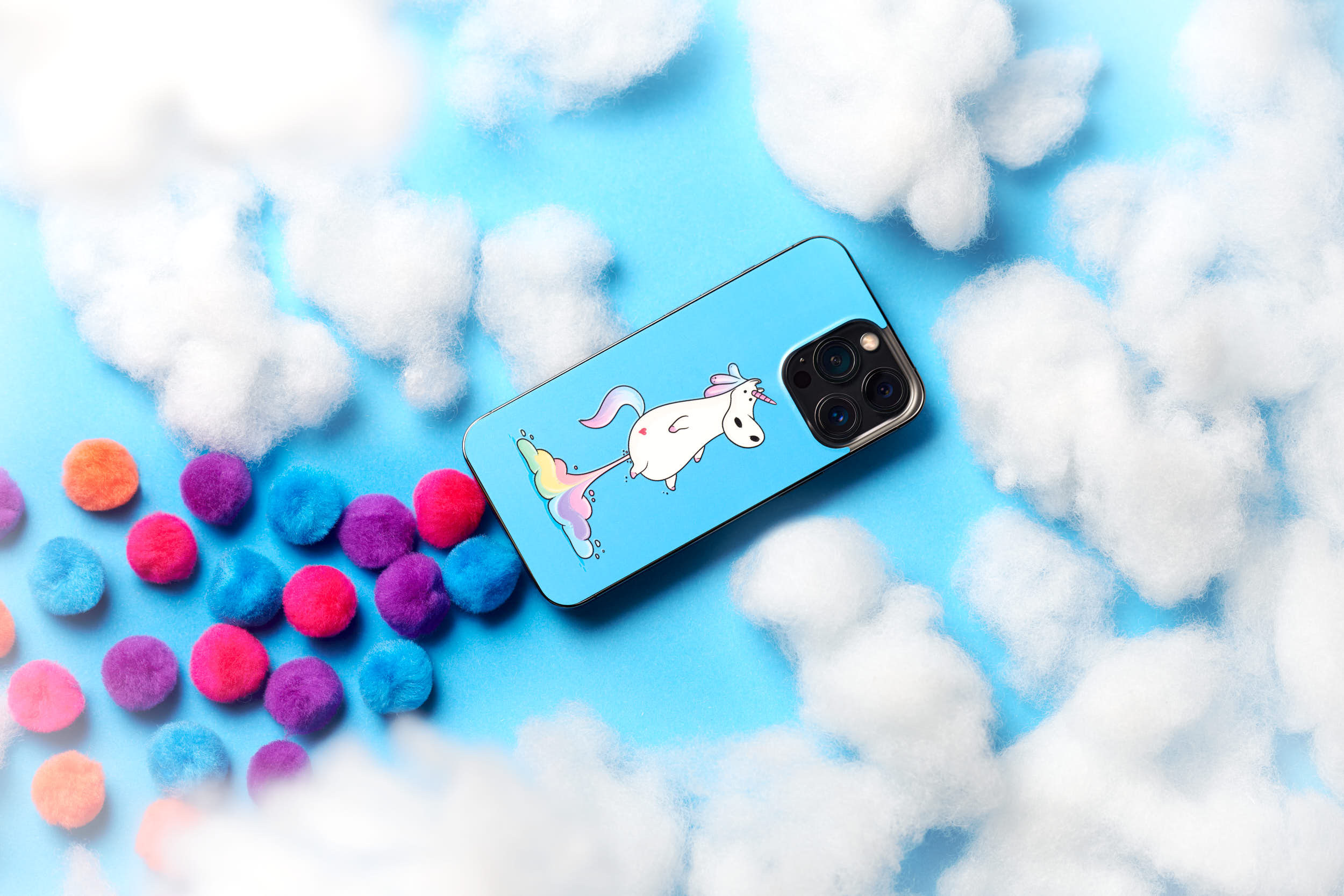 Product photo of a phone skin from Rabbiter. As the graphic of the skin, the phone is supported by colors flying through the air. With the clouds around the phone the images has a dreamy, funny and colorful concept.